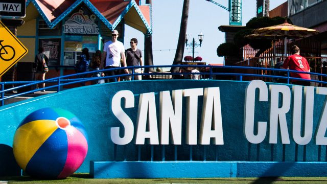 White Santa Cruz Beach sign with 1 beach ball on the left and 2 beach balls on the right of sign, northern california graduation trips