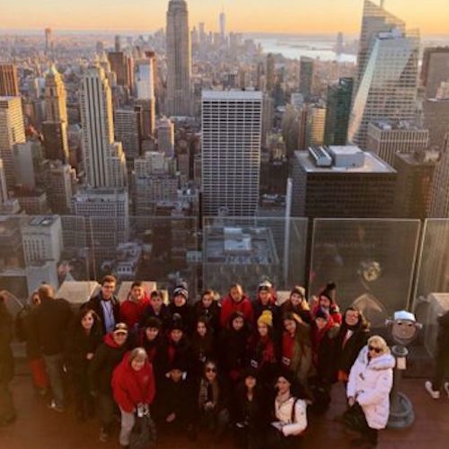 Educational Discovery Tours group on rooftop of building with New York city and the sunset in the background