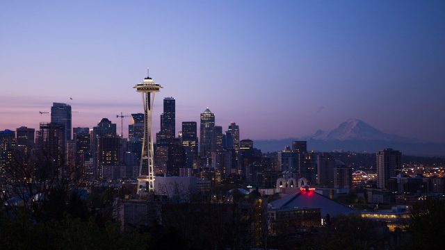 Seattle skyline at night with purple and pink skies and a mountain in the distance